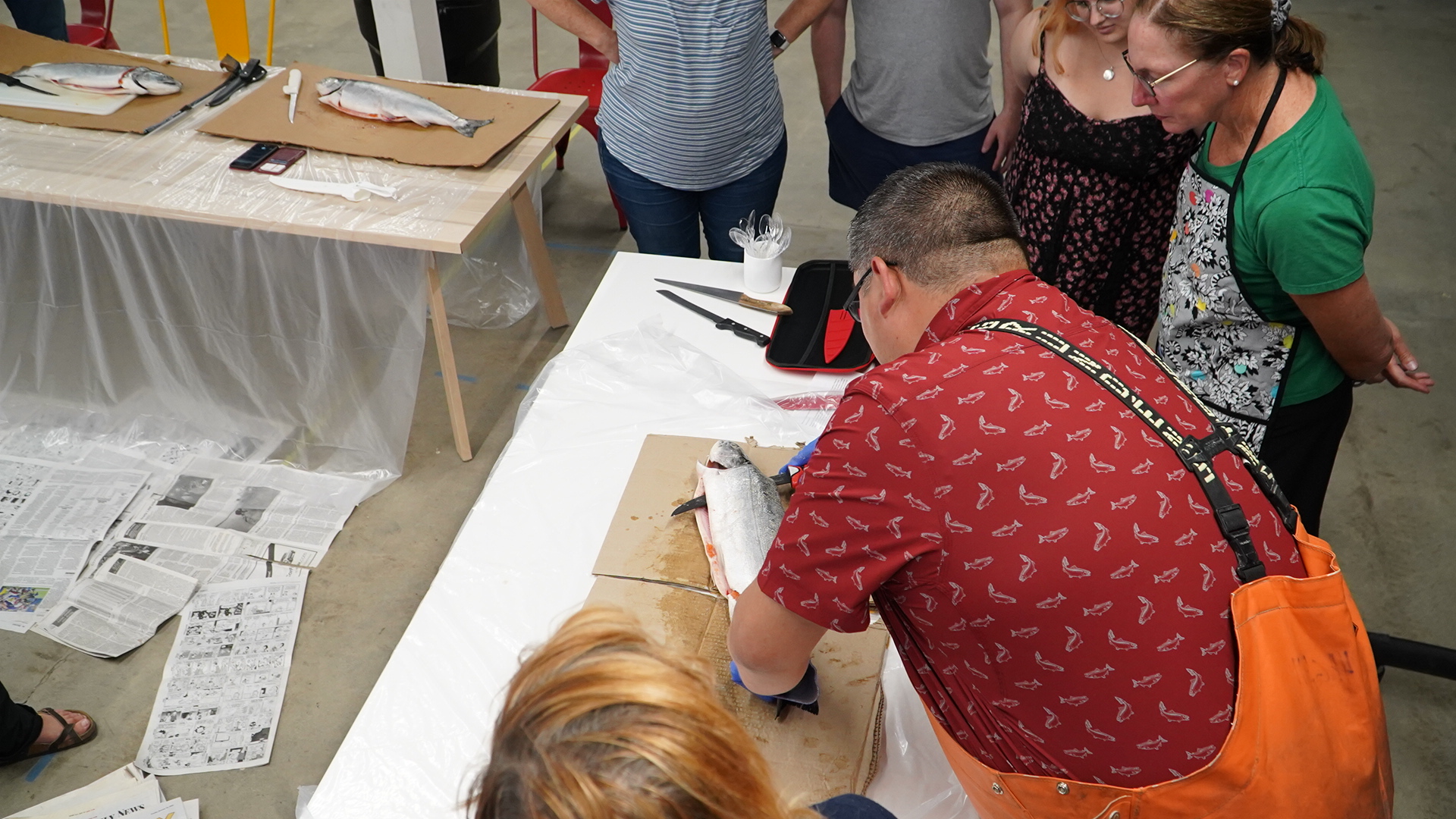 A group gathers to watch as a salmon is filleted.