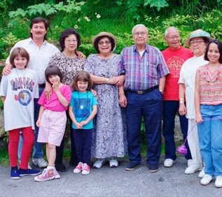 10 people stand together, posing together for a family photo.