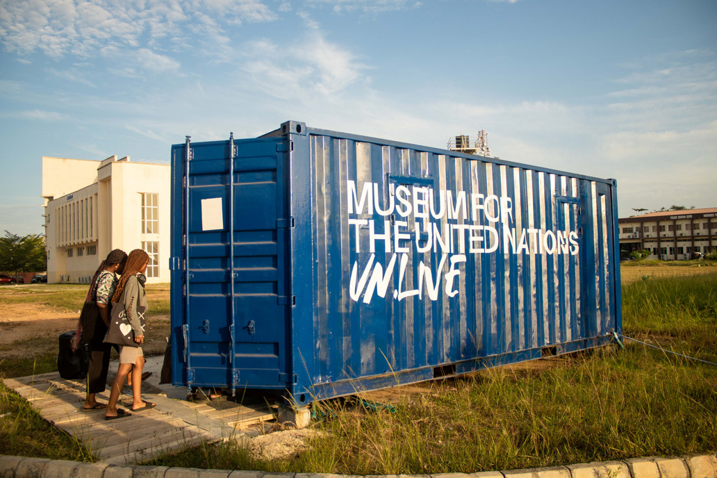 People enter a shipping container labeled "Museum for the United Nations, UN Live"